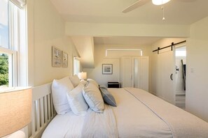 Ein Schlafzimmer mit einem großen Bett, einem Deckenventilator und einem Fenster mit Vorhängen.