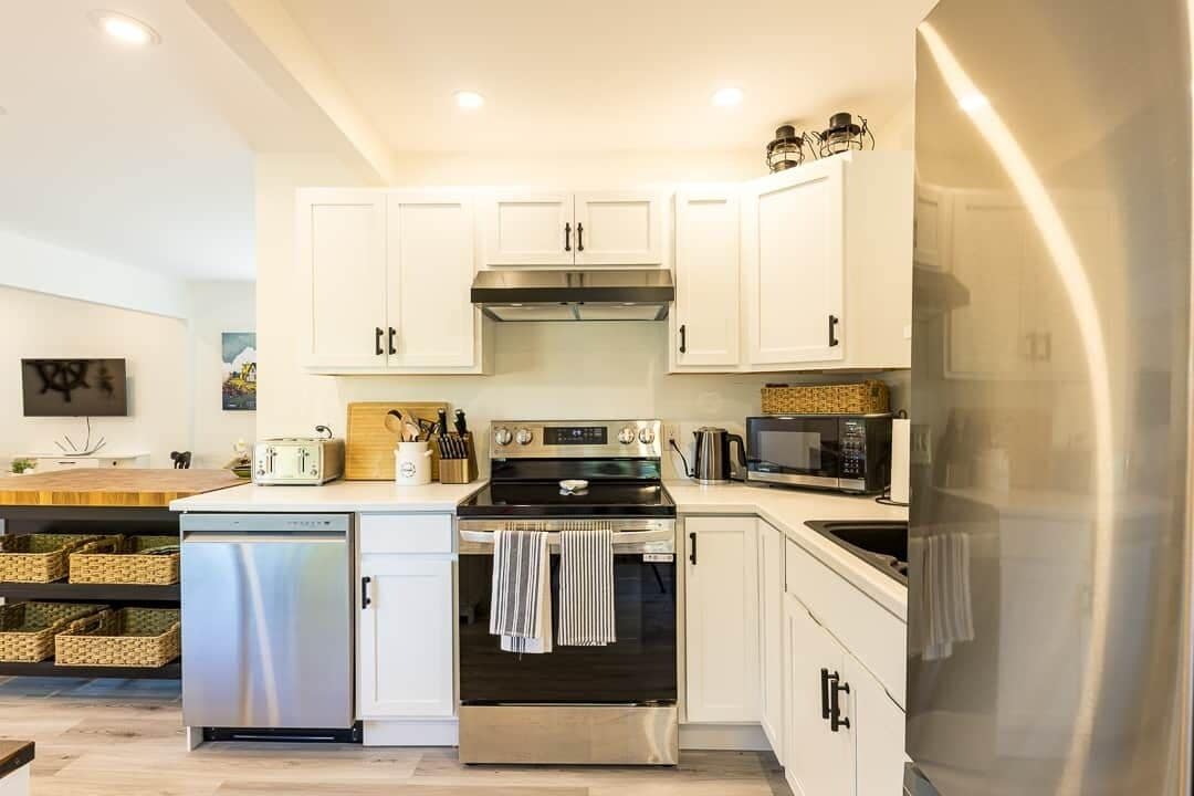 A modern kitchen with white cabinets, stainless steel appliances, and a wooden countertop.