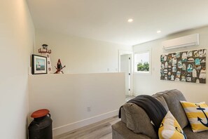 A living room with a grey sofa, a framed picture, and a wall-mounted artwork. - The White House - steps from Penderosa Beach (Prince Edward Island)