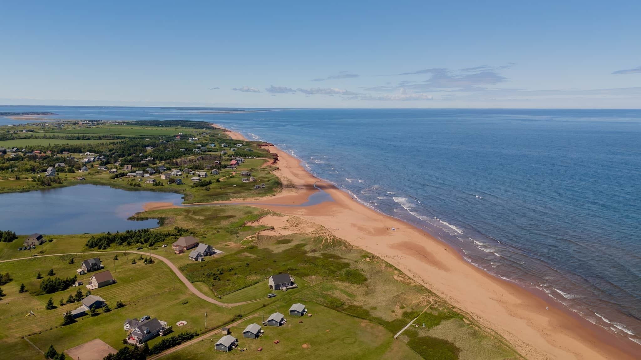 A coastal residential area with houses, a beach, and a lake.