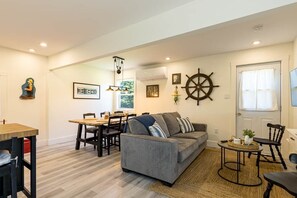 Una sala de estar con sofá, mesa de comedor, sillas y una decoración con timón de barco.