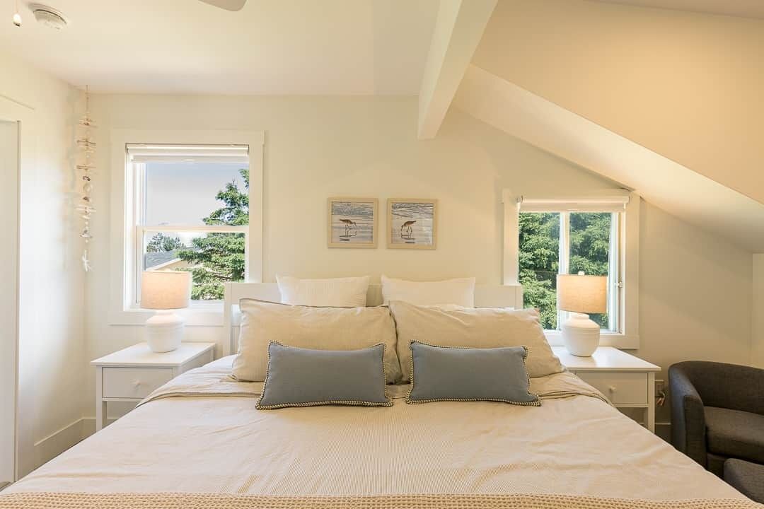 Une chambre à coucher avec un grand lit, deux tables de chevet, deux lampes et deux tableaux encadrés accrochés au mur.