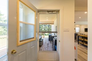 A door leading to a deck with outdoor furniture and a view of trees. - The White House - steps from Penderosa Beach (Prince Edward Island)