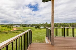 A wooden deck with a view of a green landscape and a lake. - Knights Landing in Stanley Bridge (North Rustico)