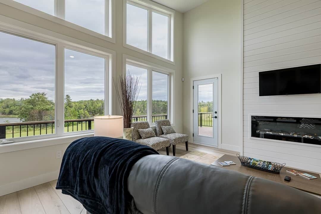 A room with large windows, a fireplace, a sofa, and a television.