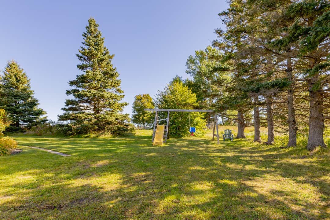 A park with a swing set, a slide, and a bench.