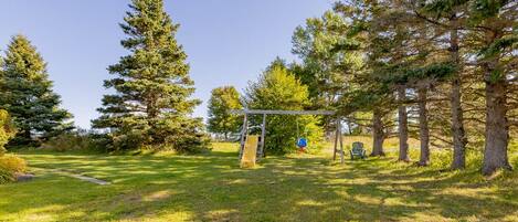 A park with a swing set, a slide, and a bench.