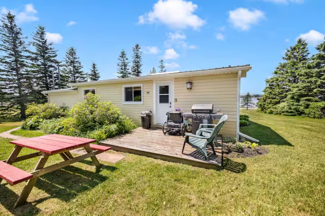 A single-story house with a patio area, a barbecue grill, and a picnic table.
