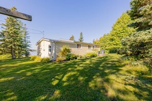 A single-story house with a front yard, a visible garage, and a clear sky. - Seawood Cottage on the Shore (North Rustico)