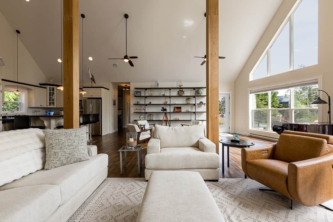 Un salon spacieux avec un plafond haut, un ensemble de canapés, une table basse et un fauteuil en cuir.