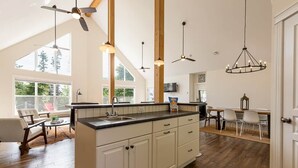 Een ruime keuken met een groot eiland, houten balken en hanglampen.
