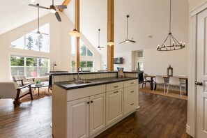 A spacious kitchen with a large island, wooden beams, and pendant lighting. - Lupin Lane Beach Retreat (Stratford)
