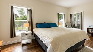 Een slaapkamer met een bed, nachtkastjes, een stoel en een boekenkast.