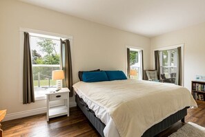 A bedroom with a bed, nightstands, a chair, and a bookshelf. - Lupin Lane Beach Retreat (Stratford)