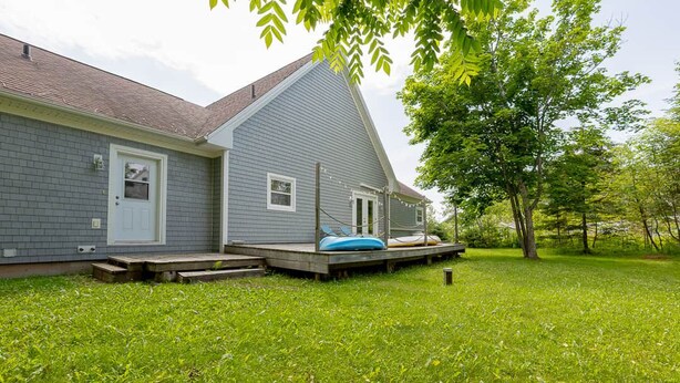 Een woonhuis met een veranda, een klein terras en een gazon.