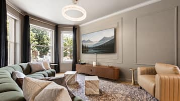 Ein modernes Wohnzimmer mit einem großen Flachbildfernseher, einer Couch, einem Couchtisch und einem gemusterten Teppich.