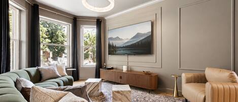 Un salon moderne doté d’un grand téléviseur à écran plat, d’un canapé, d’une table basse et d’un tapis à motifs.