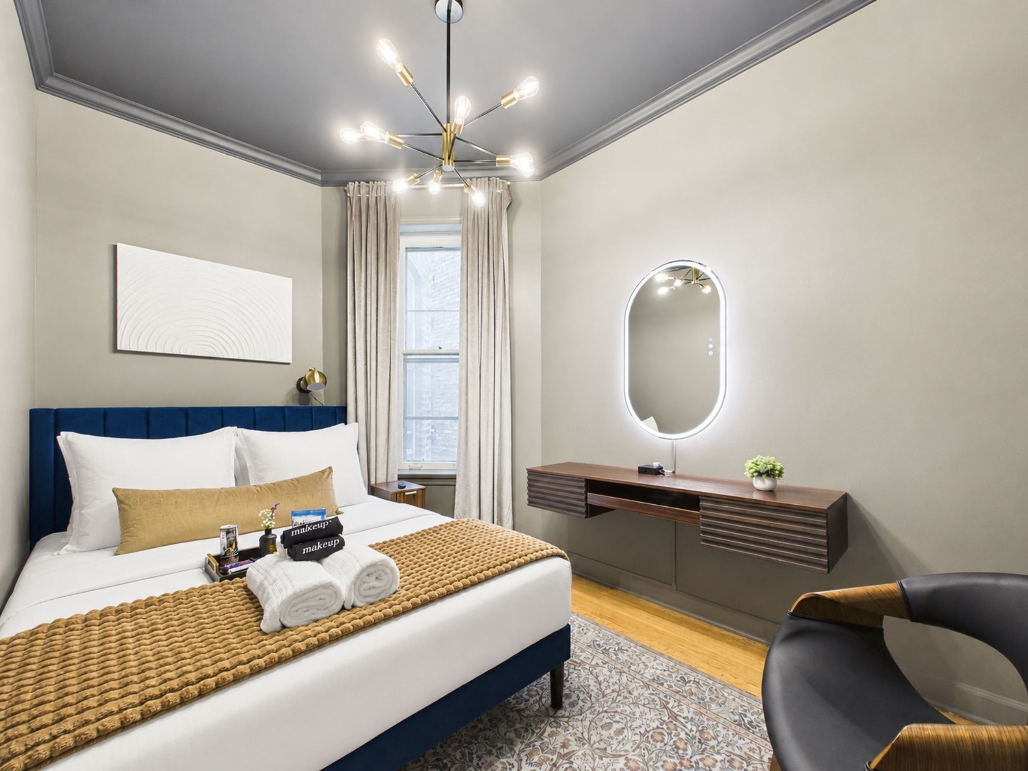 Ein Hotelzimmer mit Bett, Nachttisch, Spiegel und einem Sessel.