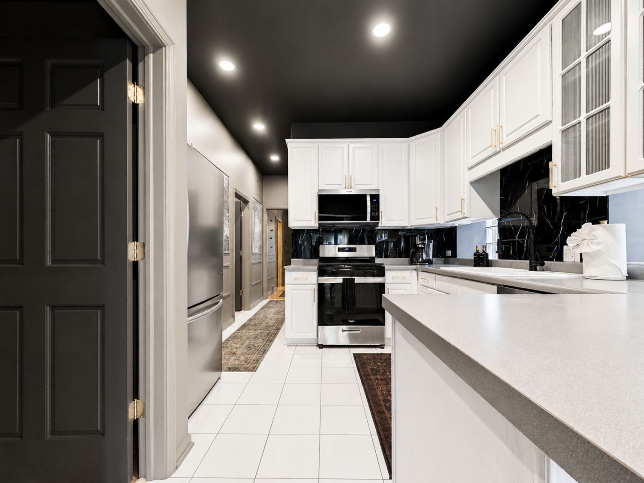 A modern kitchen with white cabinetry, stainless steel appliances, and a marble backsplash.
