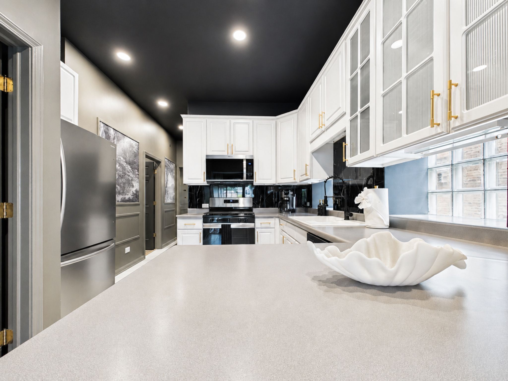 A modern kitchen with stainless steel appliances, white cabinetry, and a unique white bowl centerpiece.
