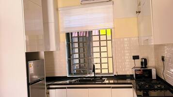 Une cuisine moderne avec des meubles blancs, un réfrigérateur en acier inoxydable, une cuisinière à gaz et un four à micro-ondes.