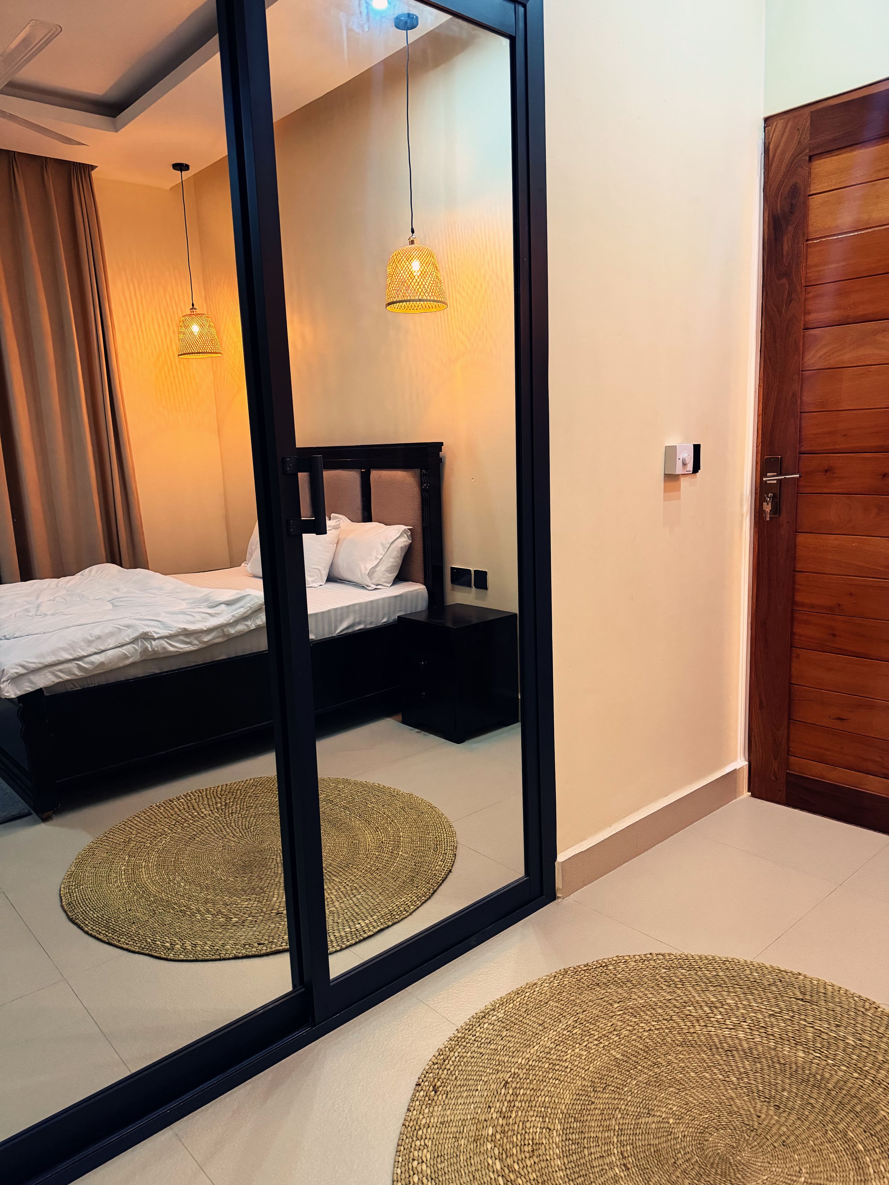 Un dormitorio con cama, mesitas de noche, un espejo y una puerta.