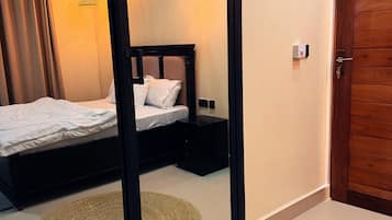 Un dormitorio con cama, mesitas de noche, un espejo y una puerta.