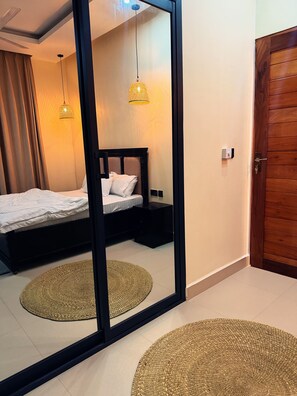Ein Schlafzimmer mit einem Bett, Nachttischen, einem Spiegel und einer Tür.