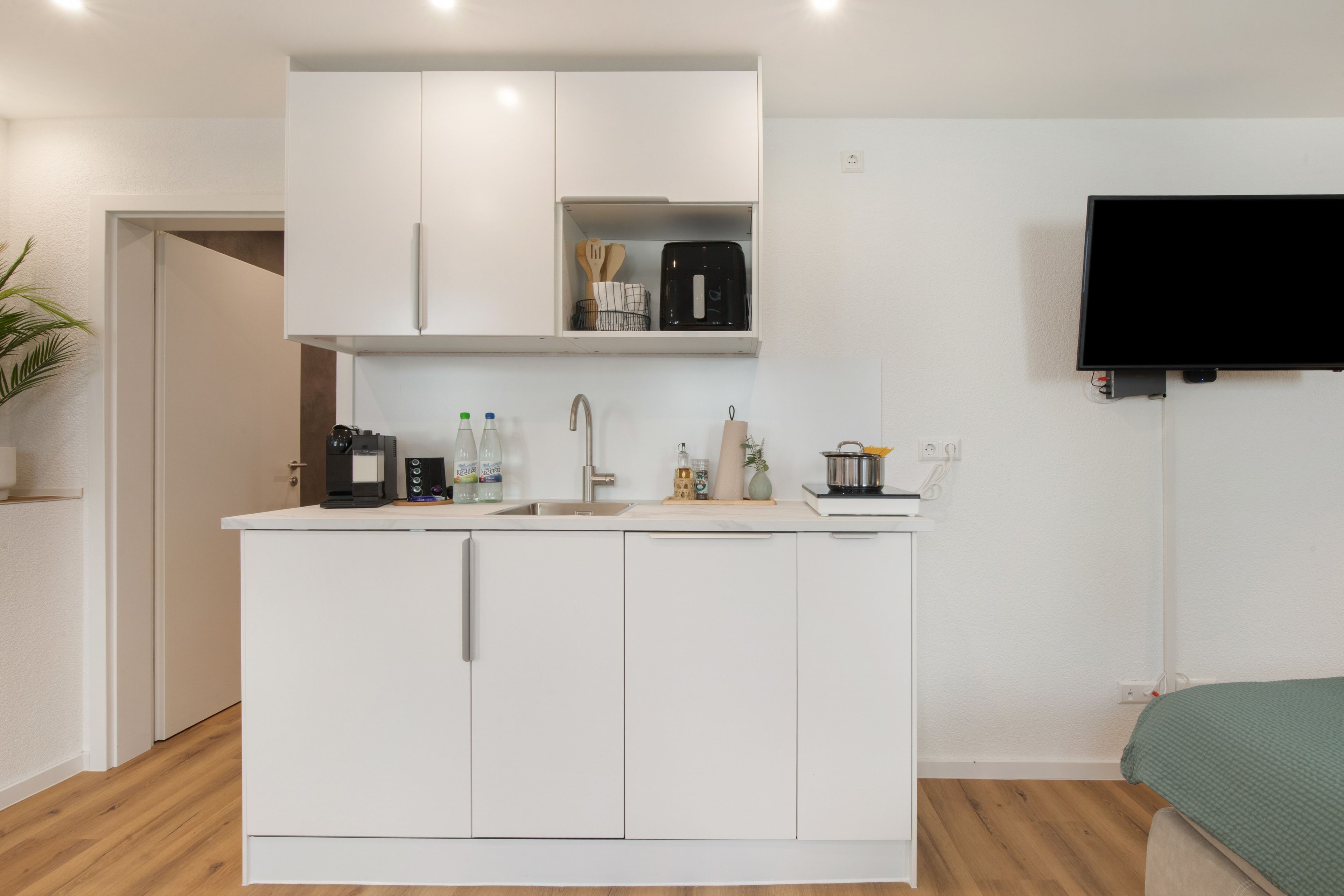 Una kitchenette compacta con horno empotrado, un lavamanos y una pequeña encimera.