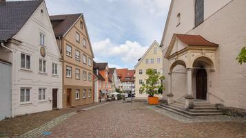 Eine Kopfsteinpflasterstraße gesäumt von traditionellen europäischen Gebäuden, darunter eine Kirche mit einem markanten Bogen.