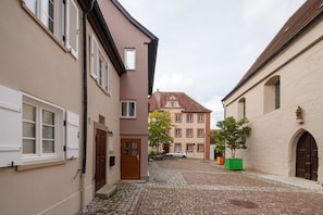 Eine Kopfsteinpflasterstraße mit Gebäuden an beiden Seiten, einer Holztür und einem geparkten Auto.