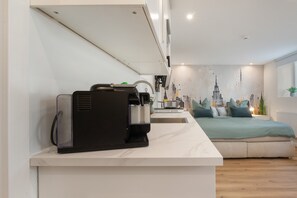 Una cuina moderna amb una màquina d'espresso integrada, un rentapeus i una placa de cocció.