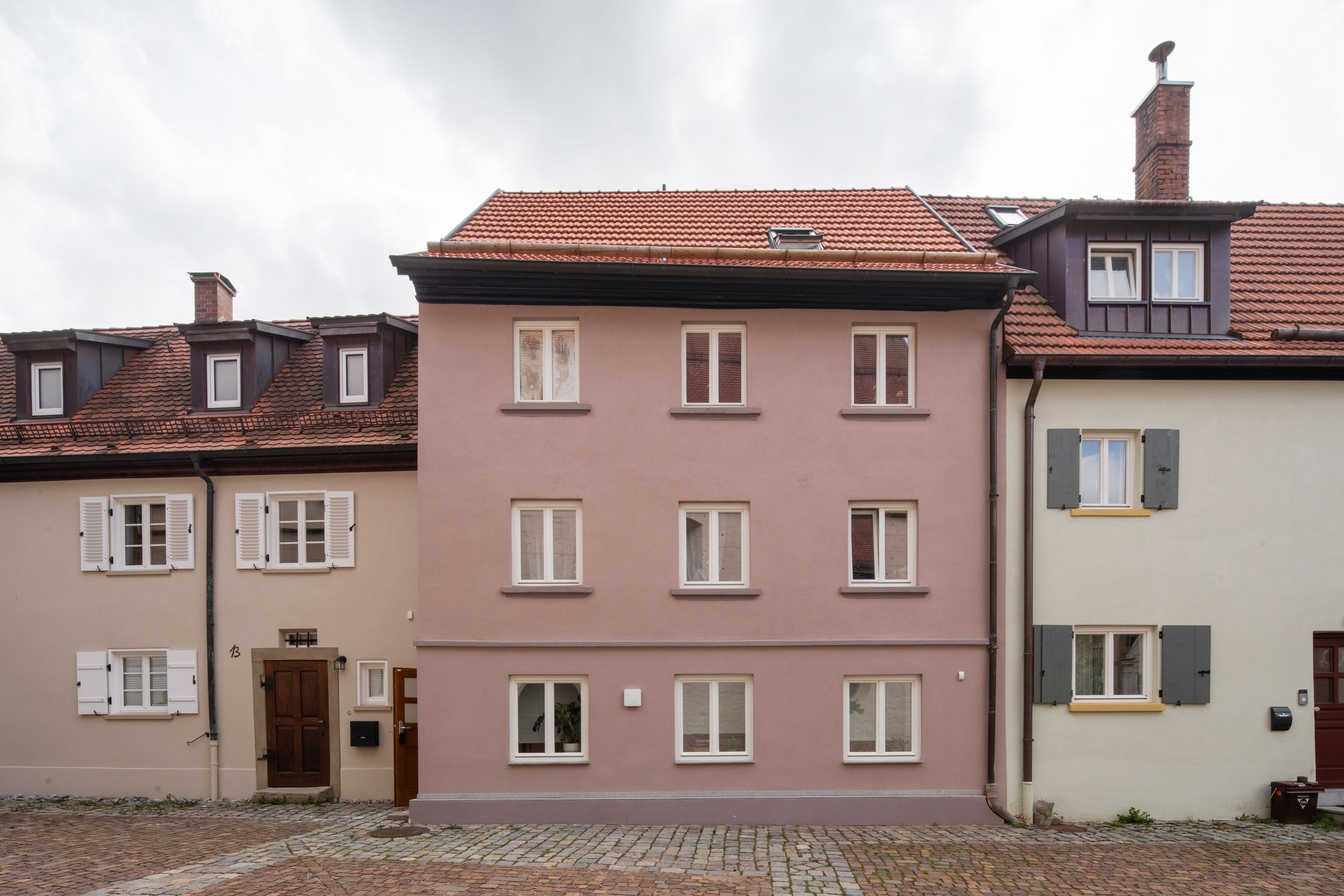 A row of multi-story buildings with uniform window designs and a cobblestone street.