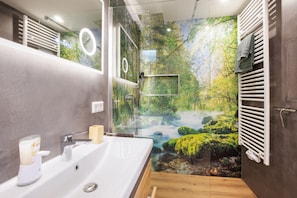 Ein modernes Badezimmer mit großem Spiegel, Waschbecken und Duschbereich.