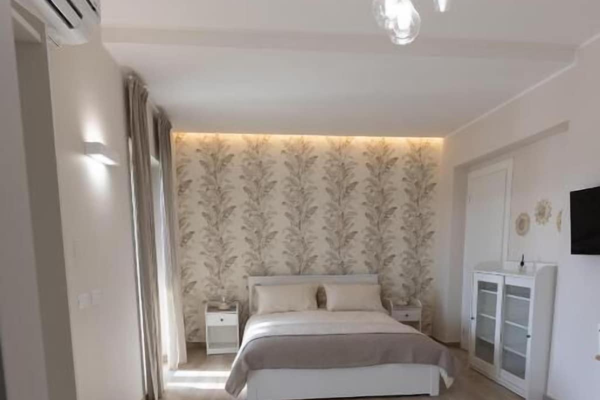 Un dormitorio con cama, mesitas de noche, armario y televisor montado en la pared.