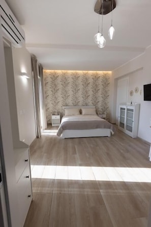 Un dormitorio con cama, mesitas de noche, armario y televisor montado en la pared.