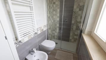 Une salle de bain comprenant des toilettes, un bidet et un espace douche.