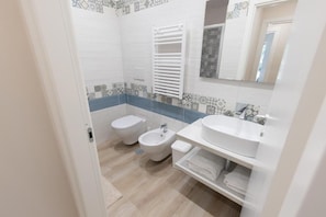 Un baño con inodoro, bidé y lavamanos.