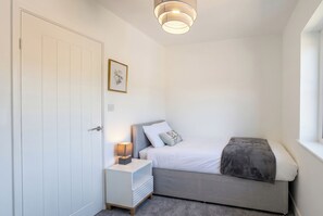 Une chambre à coucher avec un lit, une table de chevet, une lampe et un tableau encadré au mur.