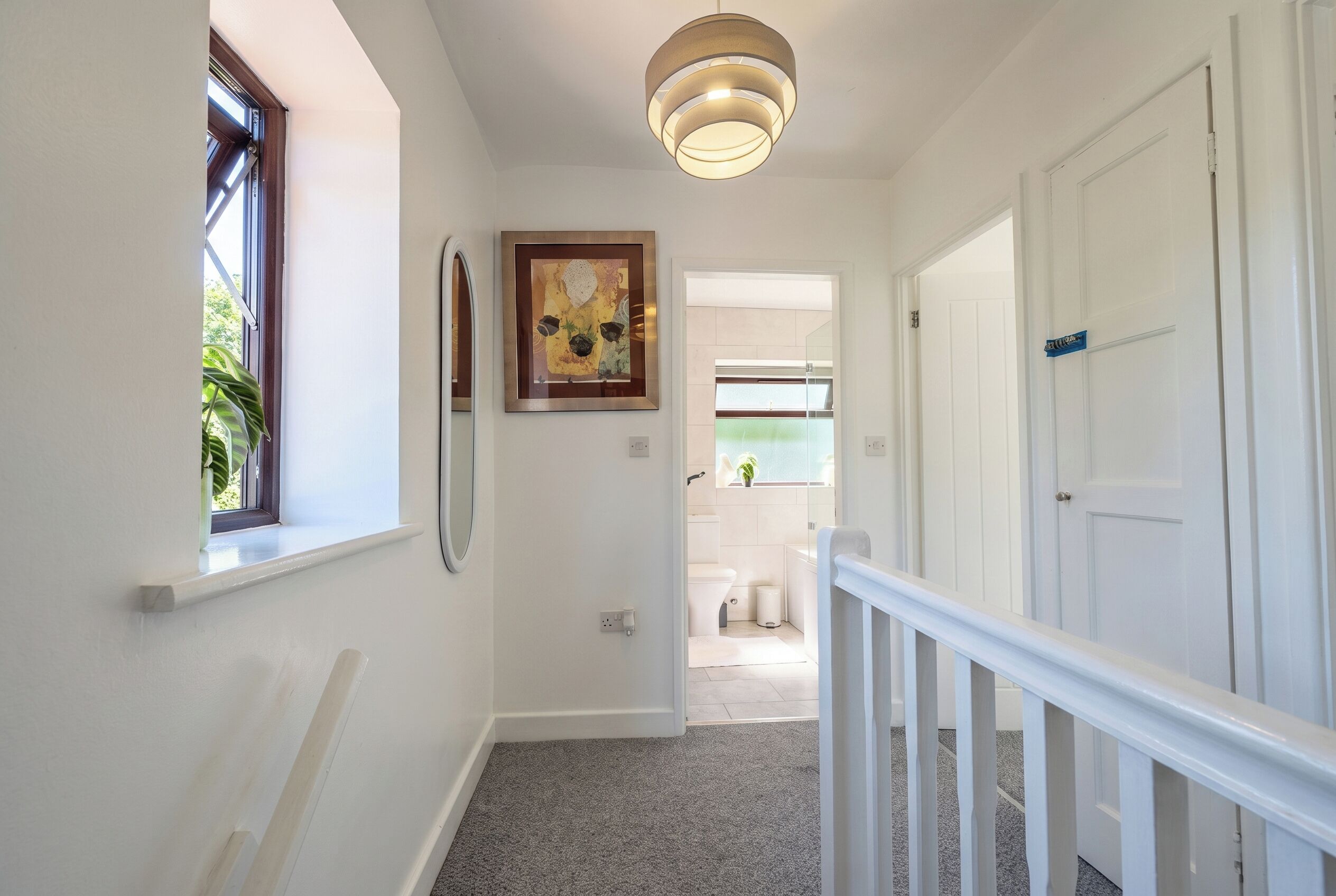 A hallway with a white door, a window, and a ceiling light fixture.
