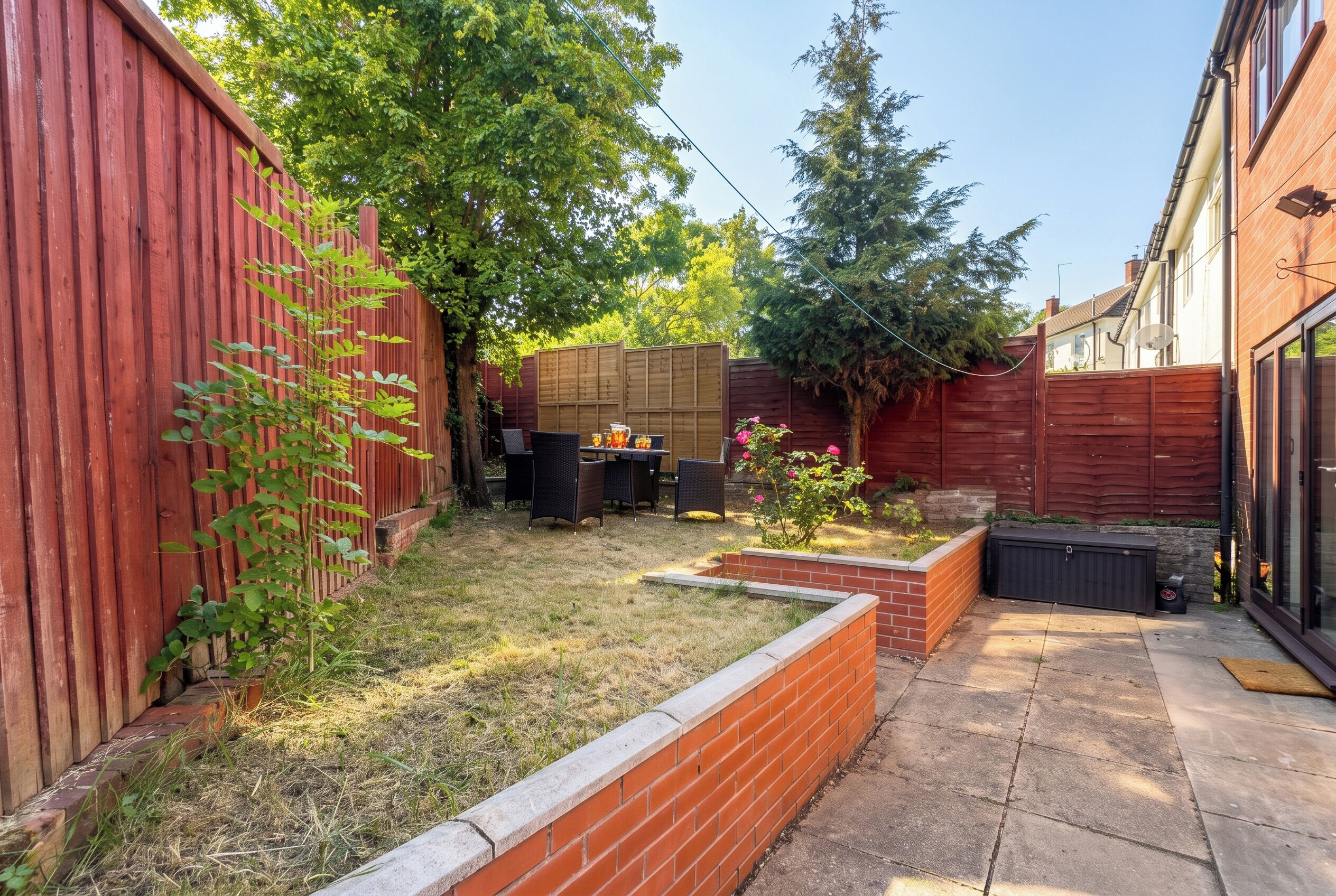 A backyard with a patio, a wooden fence, and a garden area.