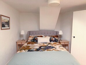 A bedroom with a bed, two bedside tables, a lamp on each table, a picture on the wall, and a door. - Cosy & private cottage nestled in the Wicklow Mountains. Pet friendly! (Tinahely)