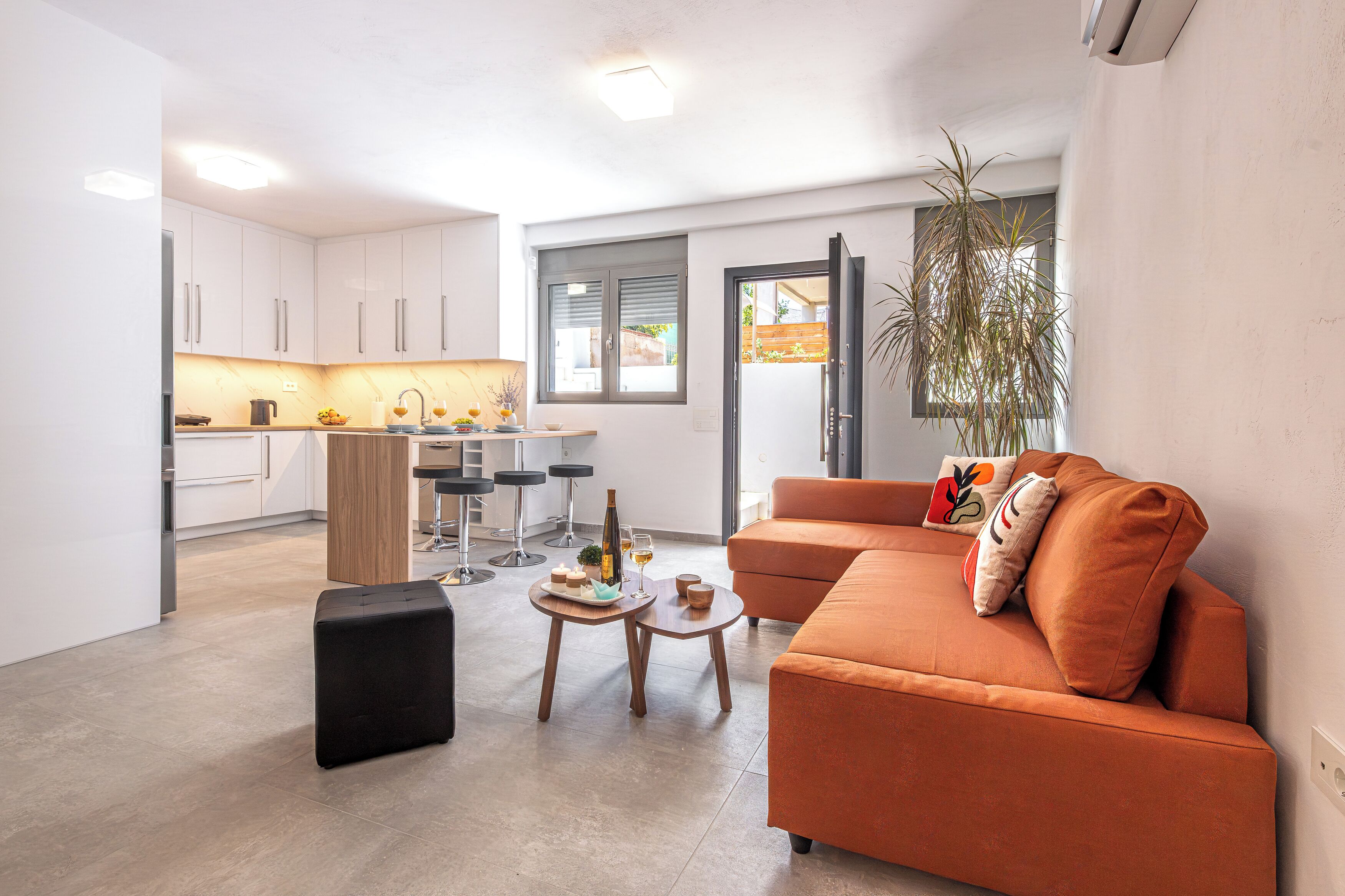 A modern living space with a sofa, a dining table, and a kitchen area.