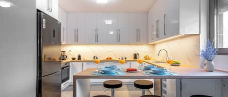 A modern kitchen with a central island, bar stools, and a built-in oven.
