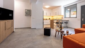 A modern kitchen with white cabinets, a built-in oven, and a window with blinds. - Bright home 200m from the Beach (Porto Rafti)