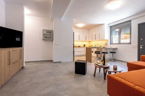 A modern kitchen with white cabinets, a built-in oven, and a window with blinds. - Bright home 200m from the Beach (Porto Rafti)
