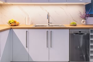 Eine moderne Küche mit einem Edelstahl-Geschirrspüler, einer Marmor-Spritzschutzwand und einer Holz Arbeitsplatte.