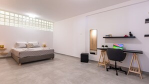A modern bedroom with a bed, bedside tables, a desk with a chair, a mirror, and a small shelf with books and a cat figurine. - Bright home 200m from the Beach (Porto Rafti)