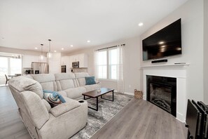 A modern living room with a sectional sofa, a fireplace, and a flat-screen TV.