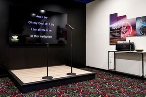 A karaoke room with a stage, a large screen displaying lyrics, and a sound system. - SwimSpa/HotTub/GameRoom/FirePit&Yard/Peloton/LUXE (Gatlinburg)